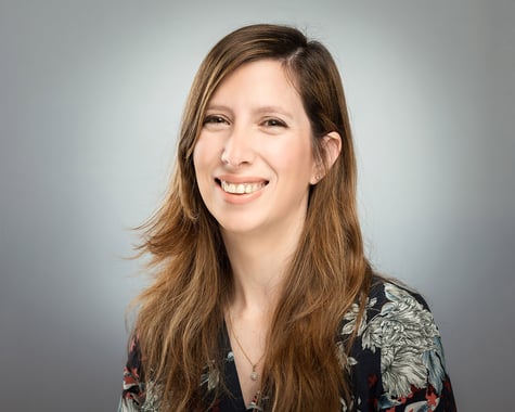 Revital Kristal, a person with long layered red hair against a grey-white background