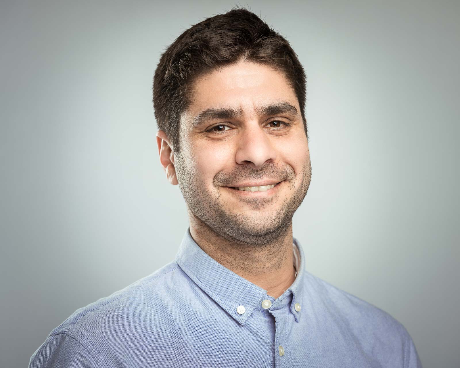 Ben Harpazi, a person with short dark hair and a light beard, against a grey-white background